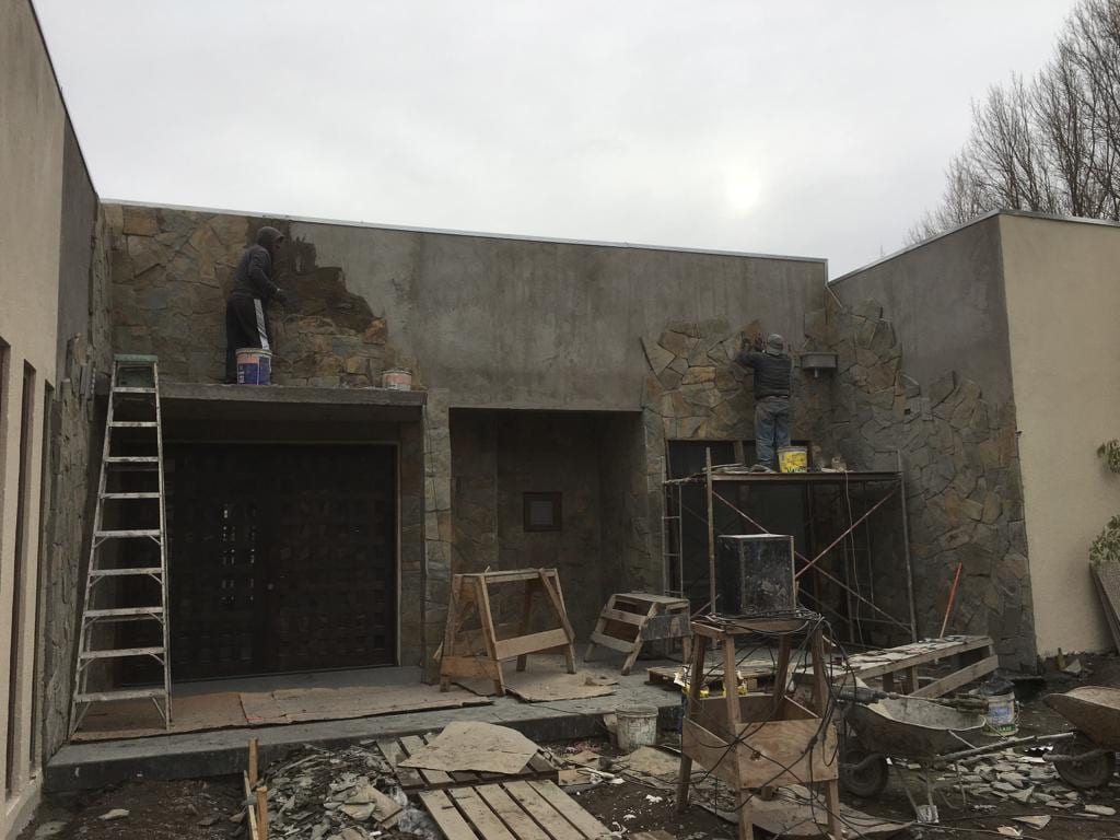 Trabajadores de Constructora LTC revistiendo con piedra la fachada de una vivienda en construcción